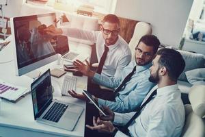 Team von Innovatoren. junge moderne männer in formalwear analysieren börsendaten während der arbeit im büro foto