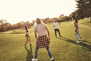 Mit Freunden Spaß haben. voller Länge von jungen Menschen in Freizeitkleidung, die Frisbee spielen, während sie unbeschwerte Zeit im Freien verbringen foto
