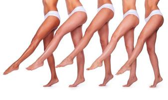 schlank und perfekt. Nahaufnahme von fünf schönen Frauen in weißen Höschen, die ihre perfekten Beine ausstrecken, während sie nahe beieinander und vor weißem Hintergrund stehen foto