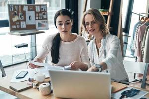 arbeiten an neuem Design. schöne junge frauen, die etwas besprechen, während sie in der werkstatt sitzen foto