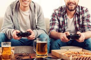 Zeit für Spiele. Zugeschnittenes Bild von zwei jungen Männern, die Videospiele spielen, während sie auf dem Sofa sitzen foto