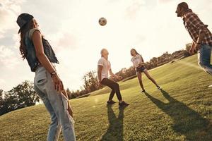 Gruppe junger lächelnder Menschen in Freizeitkleidung, die Fußball spielen, während sie im Freien stehen foto