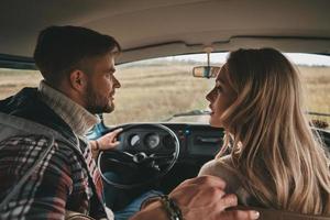 Was ist unser Ziel Schönes junges Paar, das sich unterhält, während es auf den Beifahrersitzen im Minivan im Retro-Stil sitzt foto