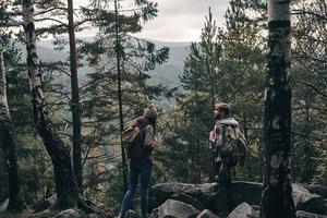 in der Mitte von Nirgendwo. junges Paar steht und schaut weg, während es gemeinsam im Wald wandert foto