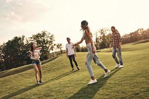aktive Spiele. voller Länge von jungen lächelnden Menschen in Freizeitkleidung, die Frisbee spielen, während sie unbeschwerte Zeit im Freien verbringen foto