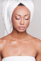frisch und sauber. schöne junge afroamerikanische hemdlose Frau, die die Augen geschlossen hält, während sie auf grauem Hintergrund steht foto