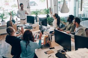 Gruppe junger moderner Menschen in eleganter Freizeitkleidung, die bei der Arbeit im Büro kommunizieren und moderne Technologien nutzen foto