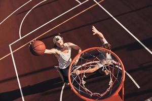 Zwei junge Männer in Sportkleidung, die Basketball spielen und lächeln, während sie Zeit im Freien verbringen foto