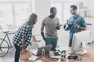 Meinungen teilen. Gruppe junger Geschäftsleute, die zusammen arbeiten und kommunizieren, während sie im Kreativbüro stehen foto