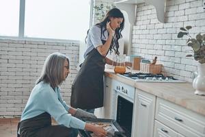 Schöne junge Frau und ihre Mutter kochen zusammen, während sie Zeit in der heimischen Küche verbringen foto