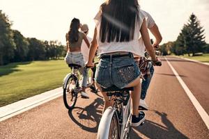 Freiheit genießen. Rückansicht von jungen Menschen in Freizeitkleidung, die zusammen Radfahren und unbeschwerte Zeit im Freien verbringen foto