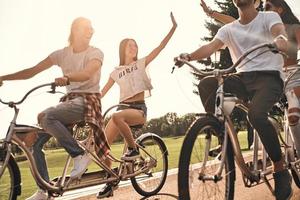 Zwei junge moderne Frauen geben sich beim Radfahren mit Freunden im Freien High Five foto