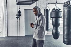 Das lange Training ist vorbei. müder junger afrikaner in sportkleidung, der wegschaut, während er im fitnessstudio steht foto