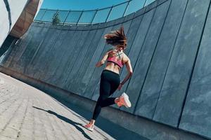 Rückansicht einer jungen Frau in Sportkleidung, die im Freien läuft foto