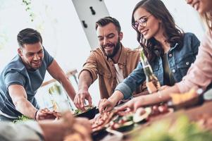 nichts ist besser als alte freunde. Gruppe junger Leute in Freizeitkleidung, die reden und lächeln, während sie eine Dinnerparty im Restaurant haben foto