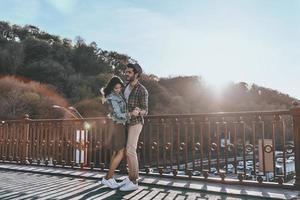 einfach verliebt. in voller Länge vom schönen jungen Paartanzen beim Stehen auf der Brücke draußen foto