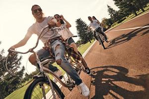 jede gemeinsame Minute genießen. Gruppe glücklicher junger Menschen in Freizeitkleidung, die beim gemeinsamen Radfahren im Freien lächeln foto