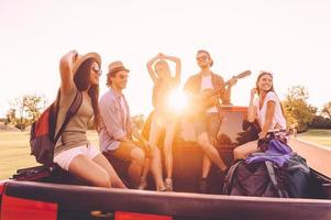 Genießen Sie den besten Roadtrip aller Zeiten. Gruppe junger, fröhlicher Menschen, die ihren Roadtrip genießen, während sie zusammen im Pick-up-Truck sitzen foto