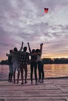 gruppe junger leute in freizeitkleidung, die selfie machen und lächeln, während sie eine strandparty am lagerfeuer genießen foto