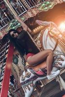 Karussell-Spaß. attraktive junge gemischtrassige Frau im roten Bikini, die Karussell reitet foto