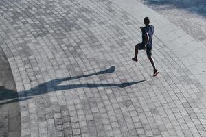 ernsthaft in Form zu bleiben. Draufsicht eines jungen afrikanischen Mannes in Sportkleidung, der beim Training im Freien joggt foto