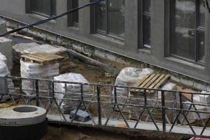 Blick auf die Baustelle, spezielle Geräte und Materialien, horizontales Foto. Hochbauprozess, Müll, Holzpaletten. Schmutzige Brücke, Sand, Wand mit Fenstern foto