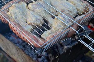 Schaschliks aus Hähnchenflügeln werden auf dem Feld gebraten. ein klassisches Barbecue unter freiem Himmel. der Prozess des Bratens von Fleisch auf Holzkohle foto
