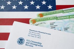 United States Permanent Resident Green Cards aus der DV-Lotterie liegen auf der Flagge der Vereinigten Staaten mit Umschlag vom Department of Homeland Security foto