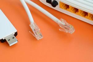 internetrouter, tragbarer usb-wi-fi-adapter und internetkabelstecker liegen auf einem leuchtend orangefarbenen hintergrund. Elemente, die für die Internetverbindung erforderlich sind foto