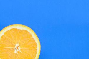Draufsicht auf eine orangefarbene Fruchtscheibe auf hellem Hintergrund in blauer Farbe. ein gesättigtes Zitrustexturbild foto