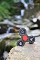 Der hölzerne Spinner liegt auf den Felsen vor dem Hintergrund eines kleinen Wasserfalls und eines Flusses foto