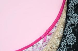 weiße, schwarze und rosa Damenunterwäsche mit Spitze auf rosa Hintergrund mit Kopierraum. Werbung für ein Geschäft mit schöner und bequemer Damenunterwäsche foto