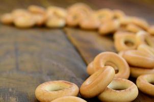 viele frische gelbe bagels liegen auf der oberfläche des alten dunklen holzes. eine beliebte Art von Mehlprodukten. eine der traditionellen russischen Leckereien für Tee foto