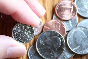 Dollarmünzen und Dollarscheine, die auf einem Holztisch verstreut sind, Dollarmünzen flach liegen. foto
