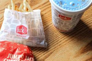 washington, usa - märz, 15 2022 jack in the box hamburger, pommes frites und gläser serviert auf einem braunen holztisch. foto