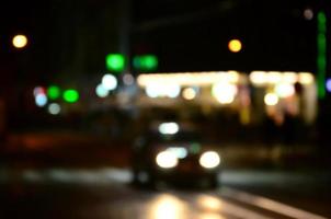 verschwommene Nachtszene des Verkehrs auf der Fahrbahn. defokussiertes Bild von Autos, die mit leuchtenden Scheinwerfern fahren. Bokeh-Kunst foto