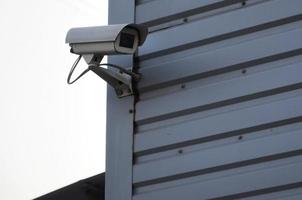 Weiße Überwachungskamera, eingebaut in die Metallwand des Bürogebäudes foto