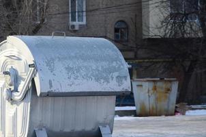 Ein silberner Müllcontainer steht im Winter in der Nähe von Wohngebäuden foto