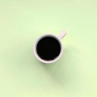 Kleine weiße Kaffeetasse auf Texturhintergrund aus modepastellfarbenem Papier foto