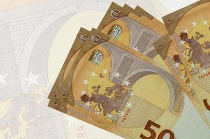50-Euro-Scheine liegen im Stapel auf dem Hintergrund einer großen halbtransparenten Banknote. abstrakte Darstellung der Landeswährung foto