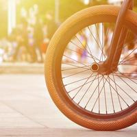 ein bmx-fahrradrad vor dem hintergrund einer unscharfen straße mit radfahrern. Extremsportkonzept foto