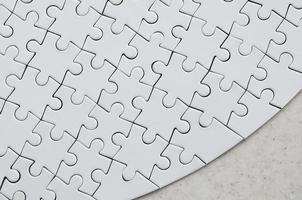 ein weißes Puzzle in der vollständigen Form liegt auf einer behandelten Steinoberfläche. strukturiertes Bild mit Kopierbereich foto