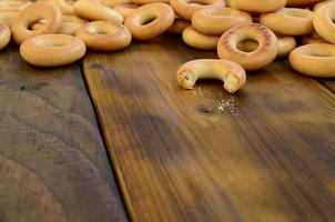 viele frische gelbe bagels liegen auf der oberfläche des alten dunklen holzes. eine beliebte Art von Mehlprodukten. eine der traditionellen russischen Leckereien für Tee foto