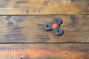 ein seltener handgefertigter zappelspinner aus holz liegt auf einer braunen hintergrundfläche aus holz. trendiges Spielzeug zum Stressabbau foto