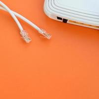 internetrouter und internetkabelstecker liegen auf einem leuchtend orangefarbenen hintergrund. Elemente, die für die Internetverbindung erforderlich sind foto