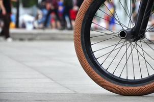 ein bmx-fahrradrad vor dem hintergrund einer unscharfen straße mit radfahrern. Extremsportkonzept foto