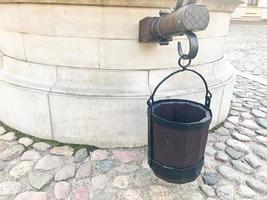 Ein alter kleiner alter antiker Eimer mit Brettern für einen Brunnen vor dem Hintergrund der gepflasterten Straße von Amenia foto