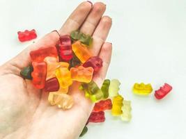 Gummibärchen liegen auf einer Hand mit einem goldenen Armband. Herstellung von Gallertbonbons. Leckereien für Kinder und Erwachsene. leckere Süßigkeiten foto