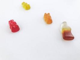 Gummibärchen auf einem weißen, matten Hintergrund. Roter, gelber und orangefarbener Bär liegen auf dem Tisch. daneben Marmelade in Form einer Flasche Limonade. Bonbons zum Dekorieren von Kuchen und Gebäck foto