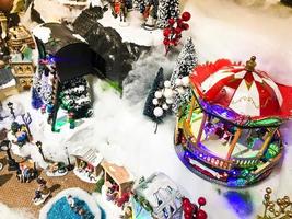 Landschaft des neuen Jahres. Spielzeugminiatur für die Vitrine. mehrstufige Komposition. In der Mitte befindet sich ein rotes Karussell für rollende Spielzeugpuppen. Dekorationen für Weihnachten foto